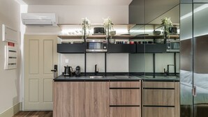 Une cuisine moderne dotée d’un îlot central, de plans de travail noirs, d’armoires en bois et d’un four à micro-ondes placé au-dessus de l’îlot.