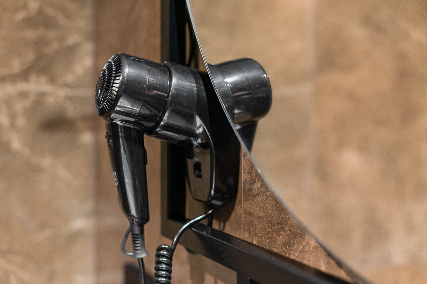 Un sèche-cheveux fixé au mur avec un câble.