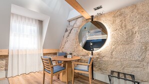A cozy dining area with a round table, wooden chairs, and a stone wall. - GuestReady - Mercadores Apartments - Room G (Porto)
