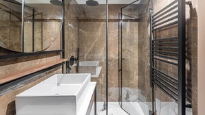 A modern bathroom with a glass shower enclosure, a large mirror, and a built-in sink. - GuestReady - Mercadores Apartments - Room G (Porto)