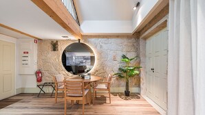 Un coin repas accueillant avec une table ronde et des chaises, une plante en pot et un mur en pierre.