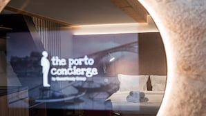 Une chambre d’hôtel avec un lit, une table de chevet et une lampe. La chambre présente un design moderne, avec un plafond en bois et une grande fenêtre.