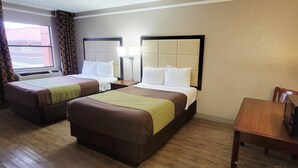 Una habitación de hotel con dos camas, un escritorio de madera y una silla.