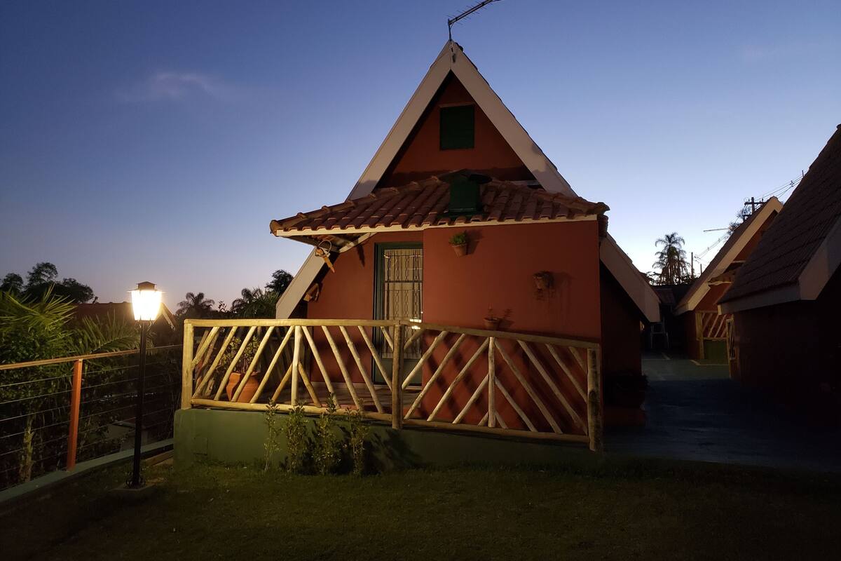 Un petit bâtiment à toit triangulaire, entouré d’une clôture en bois et agrémenté d’un lampadaire.