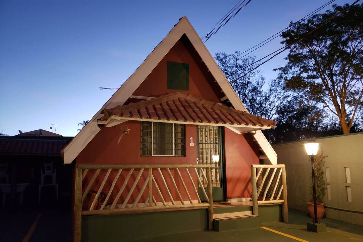 Un petit bâtiment à toit rouge, doté d’un porche verdoyant et d’une seule fenêtre.
