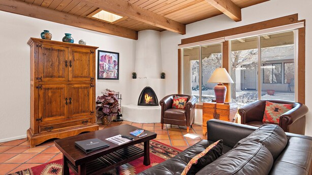 Un salon chaleureux avec une cheminée, un canapé en cuir, un meuble en bois et de grandes fenêtres.