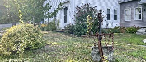 A white house with a front yard, a metal gate, and a stone wall.