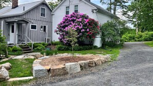 A two-story house with a porch and a driveway leading to a gravel path. - Charming, updated 3 bedroom farmhouse farm stay.  (Williamsburg)