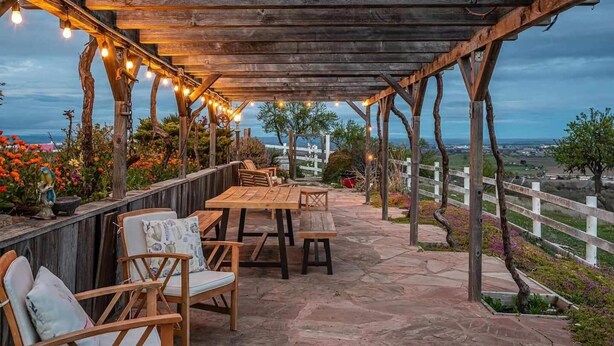 A covered outdoor seating area with wooden furniture and string lights. - FarmStay HillTop wine country views 6BR/4BA (Paso Robles)