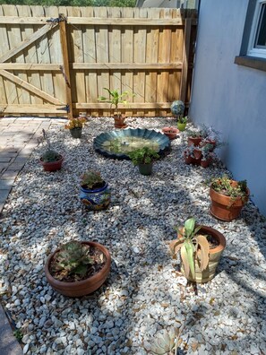 Een tuin met diverse plantenpotten en een decoratieve vijver.