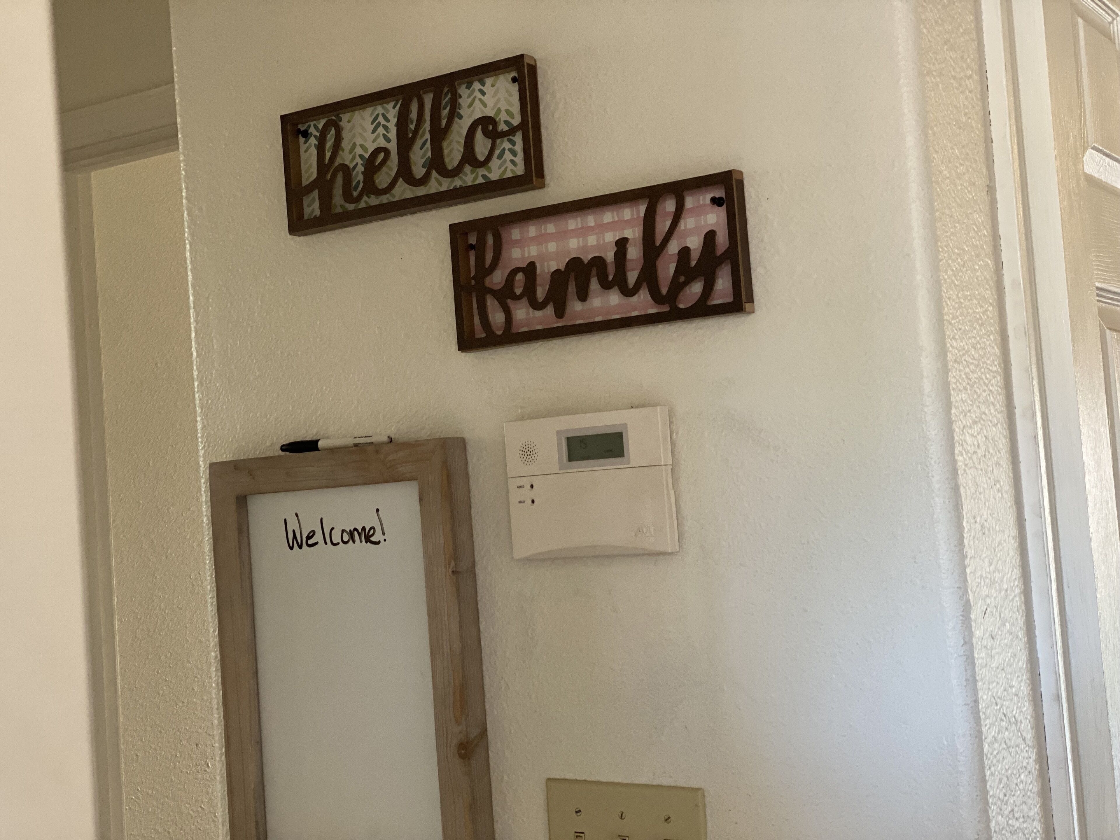 A wall with three wooden signs reading "hello," "welcome," and "family."