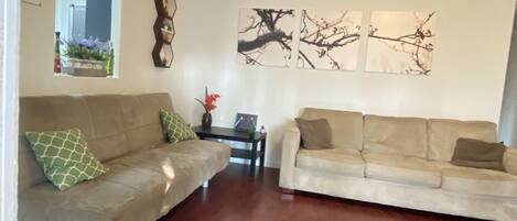 A living room with two beige sofas, a patterned rug, and wall art.