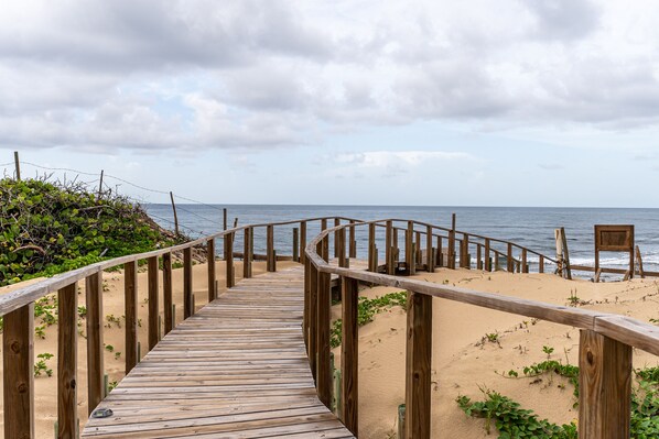 A wooden boardwalk leading to a beach with a sandy shore and a cloudy sky. - 3 Bedroom Oceanfront Beach House (Isabela)