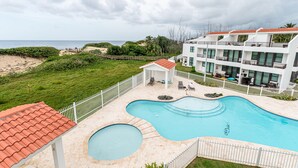 A swimming pool with a unique shape, surrounded by a white fence, and adjacent to a building with balconies. - 3 Bedroom Oceanfront Beach House (Isabela)