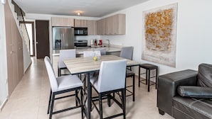 A modern kitchen with stainless steel appliances, a dining area with a wooden table and chairs, and a living area with a leather sofa. - 3 Bedroom Oceanfront Beach House (Isabela)