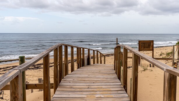 A wooden boardwalk leading to a beach with the ocean in the background. - 3 Bedroom Oceanfront Beach House (Isabela)