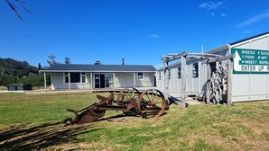 A rustic building with a sign listing amenities like beds, showers, food, gift shop, insect repellent, and an entrance ramp. - Rarakau Lodge (Rowallan)