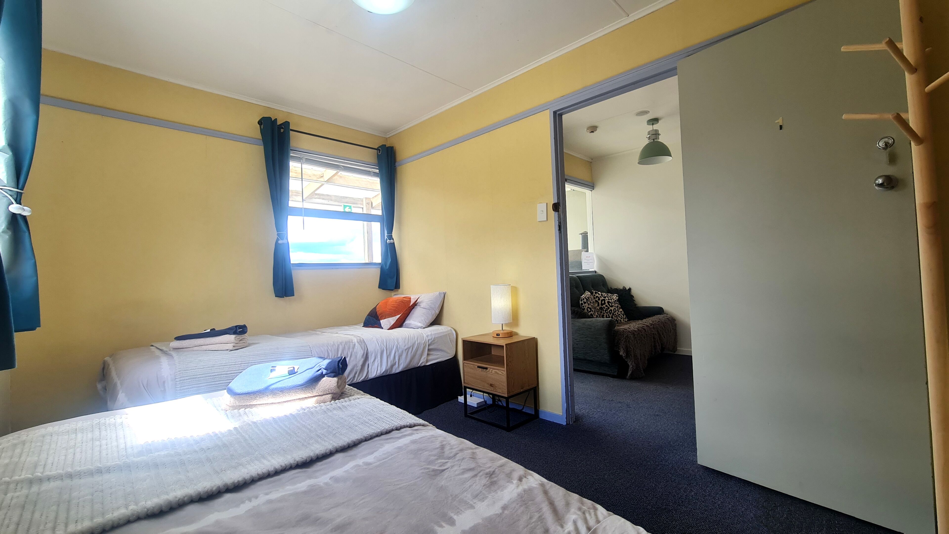 Ein Zimmer mit zwei Betten, einem Nachttisch mit Lampe, einem Spiegel und einem Kleiderschrank.
