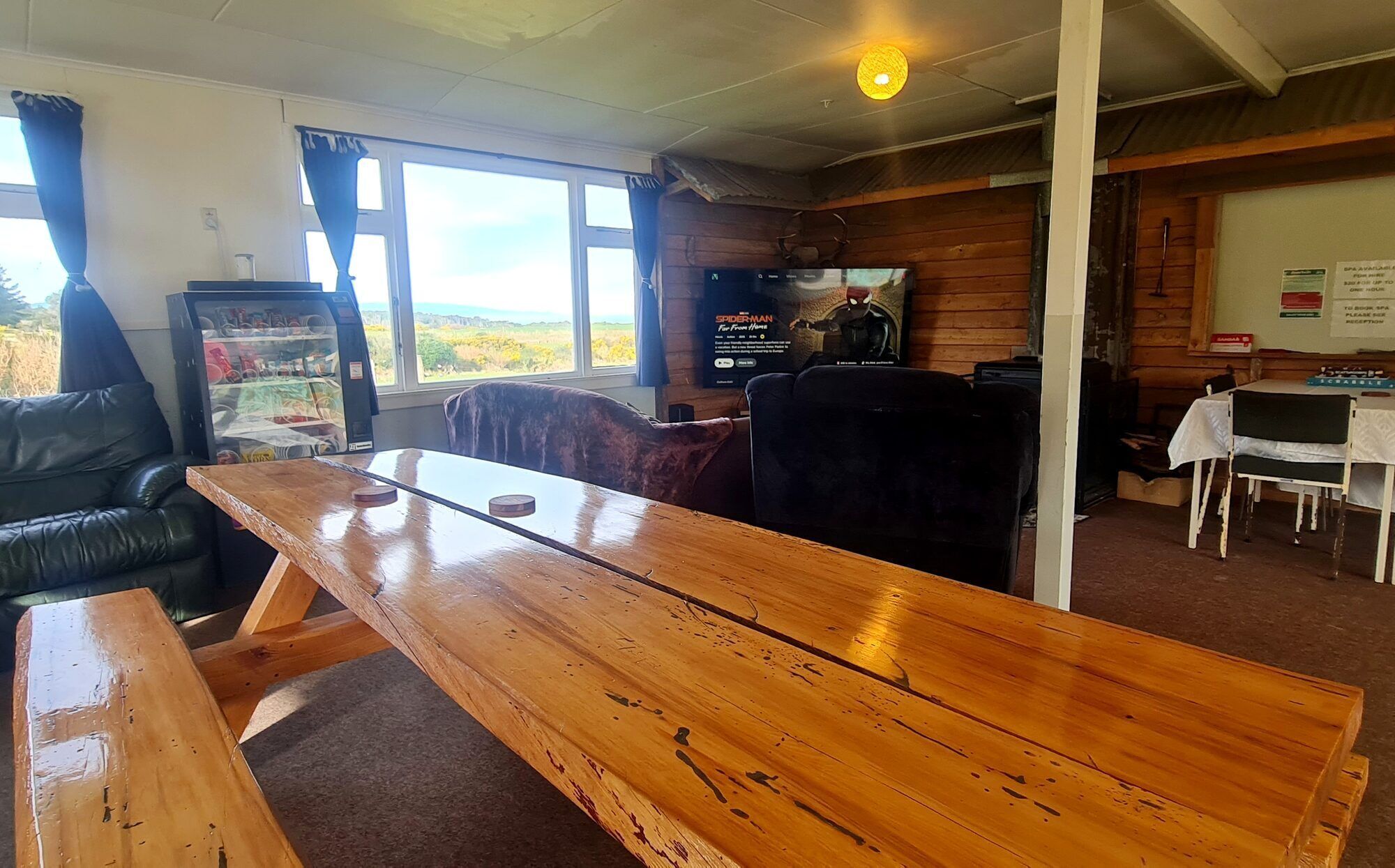 Una mesa de madera en una habitación con vistas, un refrigerador y un televisor.