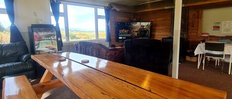 A wooden table in a room with a view, a refrigerator, and a television.