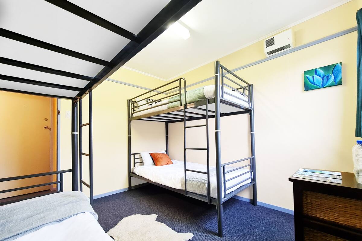 A bunk bed room with a wooden door, a small desk, and a painting on the wall.