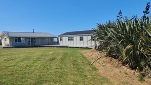 A two-story house with a large lawn, a satellite dish, and a garden with tall plants. - Rarakau Lodge (Rowallan)