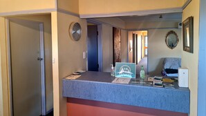 A reception desk with a clock, a framed mirror, and a sign reading "RARAKAU". - Rarakau Lodge (Rowallan)