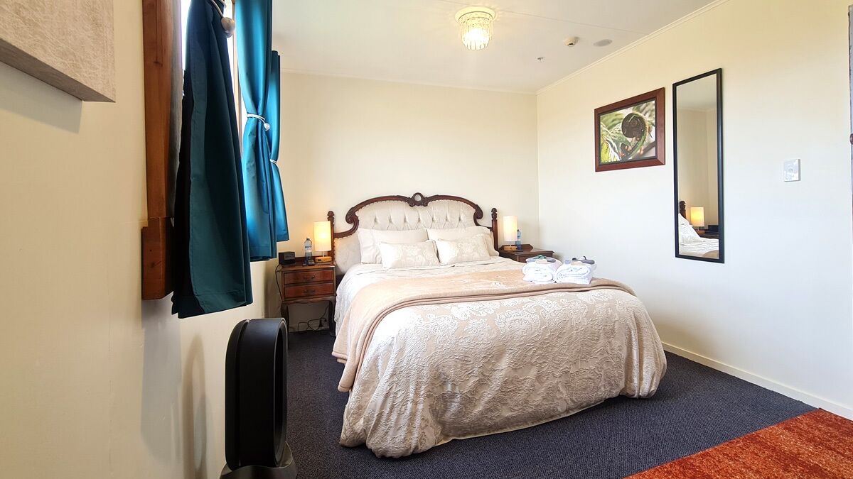 A bedroom with a bed, bedside tables, a mirror, and a wall-mounted artwork.