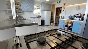 A modern kitchen with a gas stove, white cabinets, and a coffee machine.