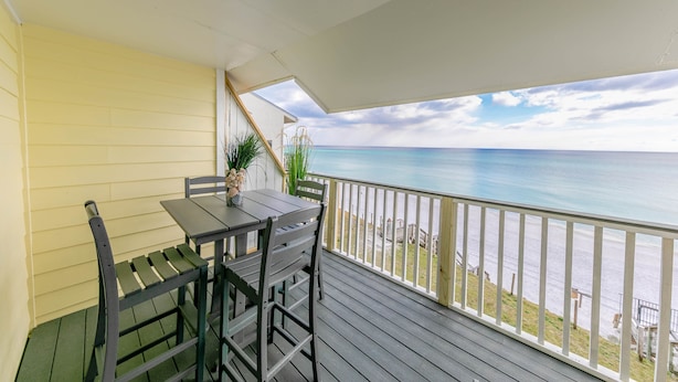 A balcony with a table and chairs, overlooking a beach and ocean. - 30A Gulf front 2 Bed/2 Bath Sleeps 6 Private beach- Beach service included (Santa Rosa Beach)