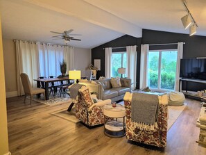 A living room with a sofa, chairs, a dining table, and a TV.