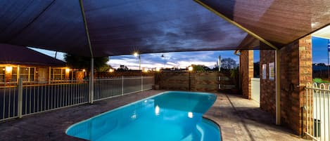 Una piscina al aire libre, sillones reclinables de piscina