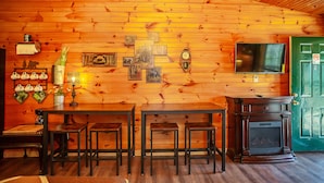 A wooden interior with a fireplace, a television, and a green door. - Bigfoot Lodge Room One (Benton)