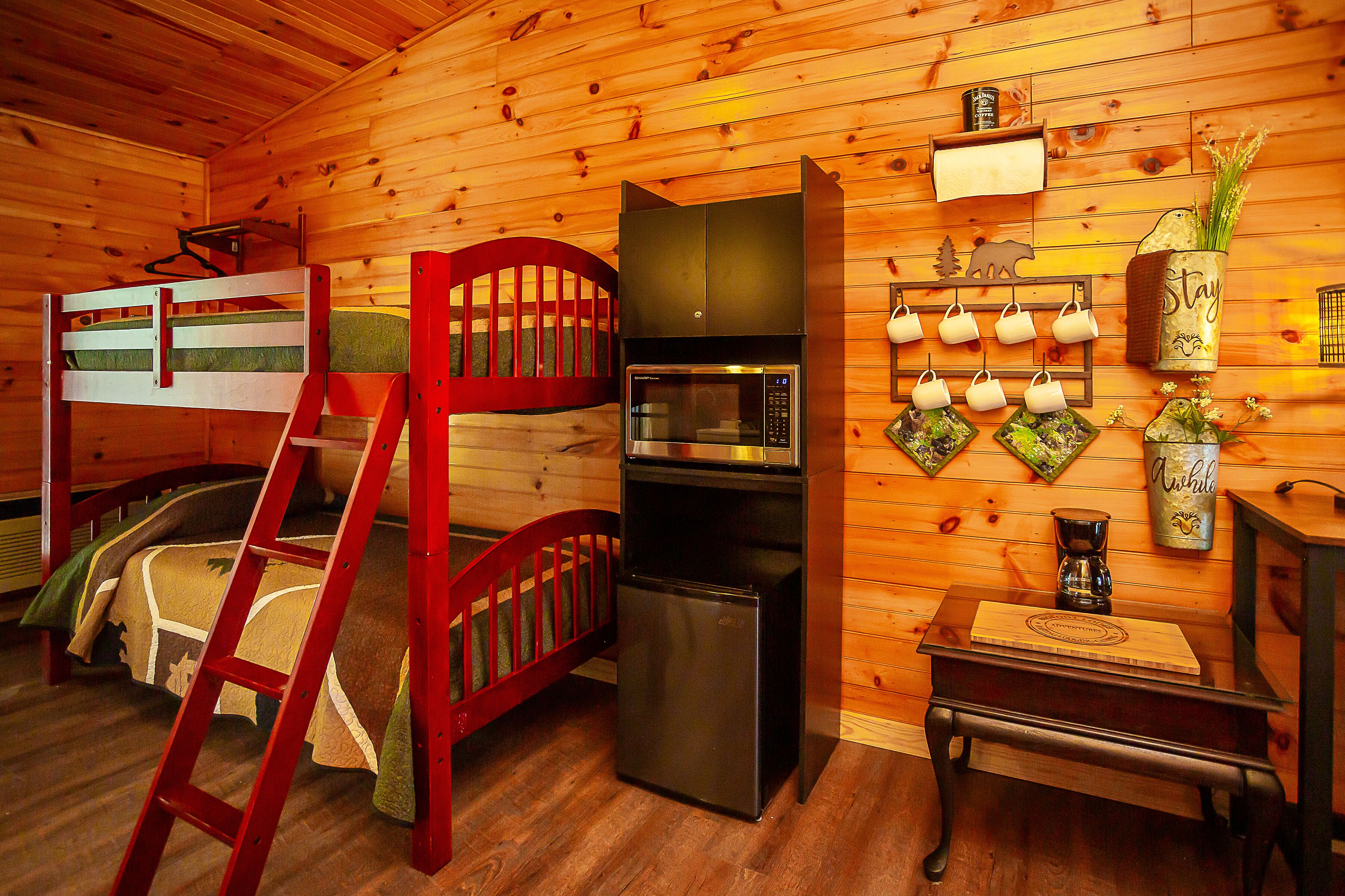 A cozy cabin interior with a bunk bed, a refrigerator, a microwave, and a wall-mounted coffee maker.