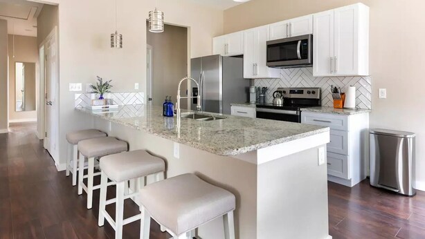A modern kitchen with a large island, stainless steel appliances, and bar stools. - Cozy Home near Alamodome~Free Gated Parking~Kids Climbing Dome & Backyard games (San Antonio)