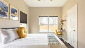 A bedroom with a large bed, a desk, and a chair. - Cozy Home near Alamodome~Free Gated Parking~Kids Climbing Dome & Backyard games (San Antonio)