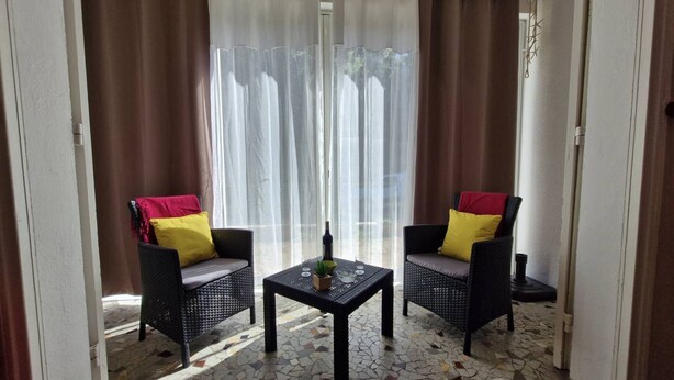 Una habitación con dos sillones de mimbre, una mesita y una botella.