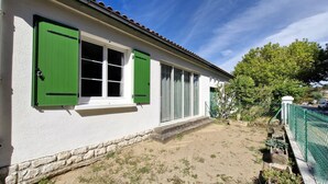 Una casa con fachada blanca, contraventanas verdes y base de piedra.
