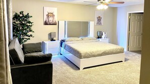 Un dormitorio con cama, mesita de noche, lámpara, ventilador de techo y puerta.