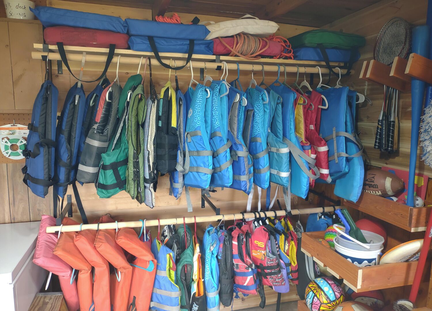A storage area with various life jackets and safety gear hanging on racks.
