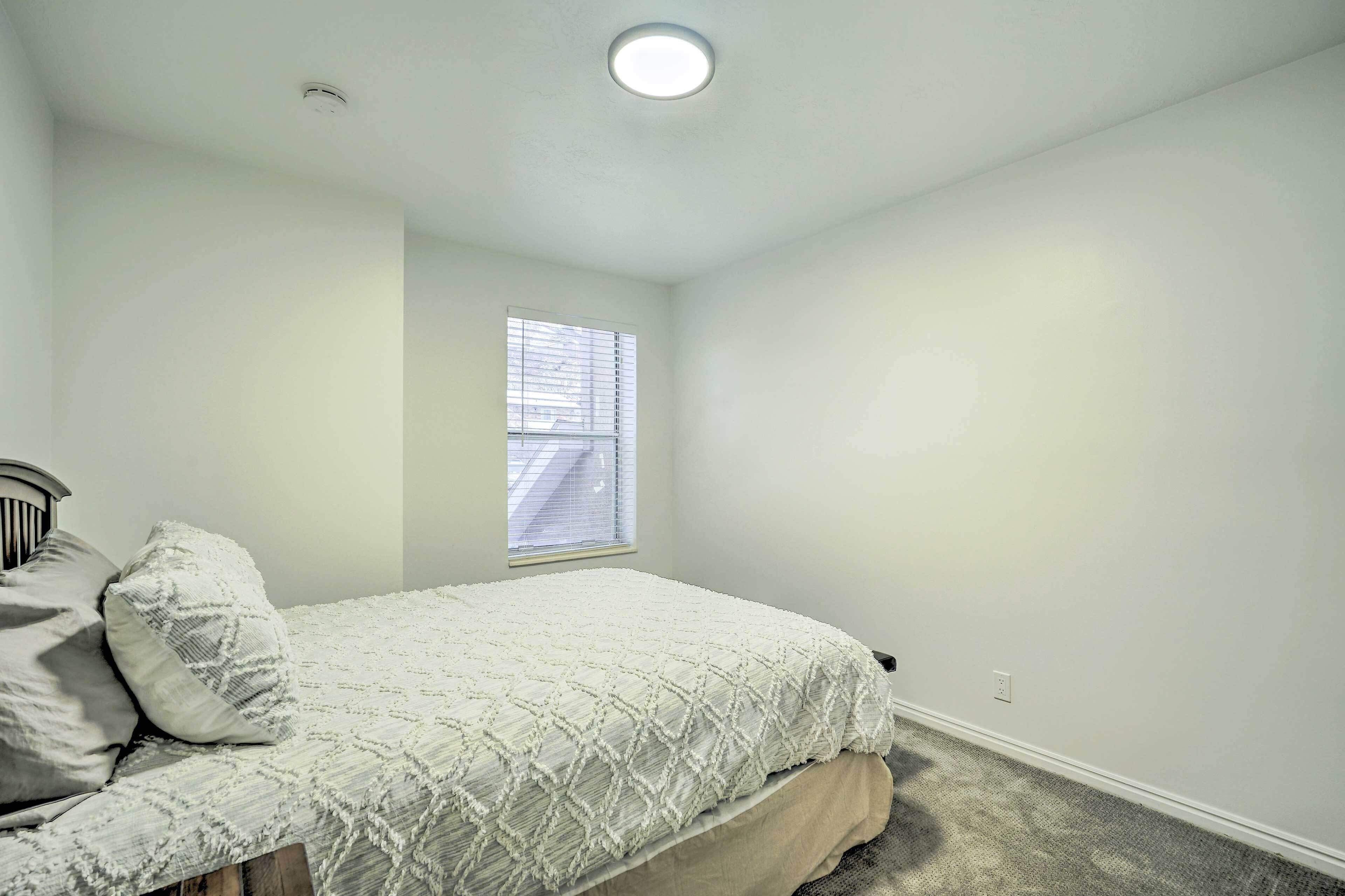 A bedroom with a bed, a window, and a ceiling light.