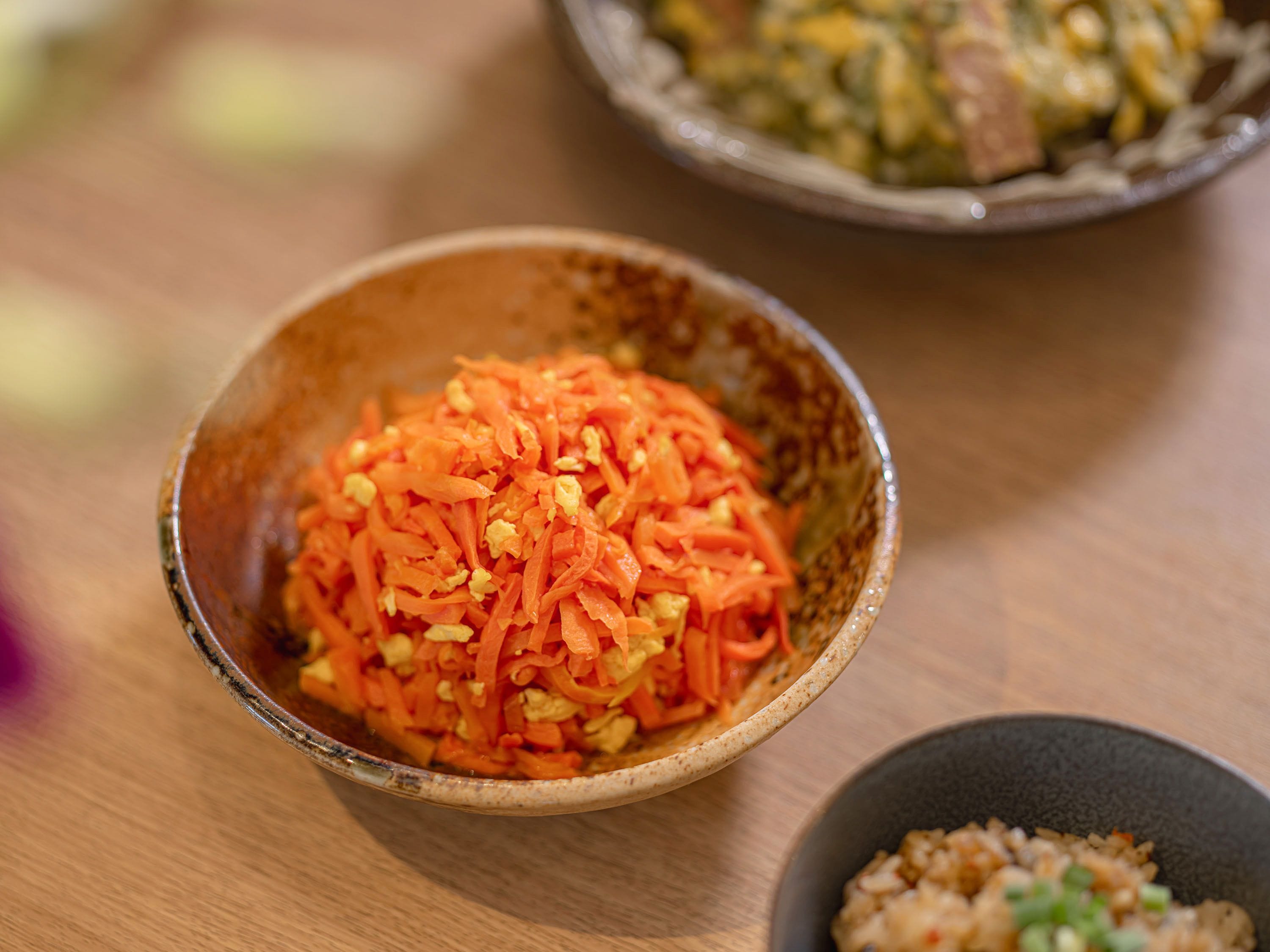 A bowl of shredded carrots with a blurred background.