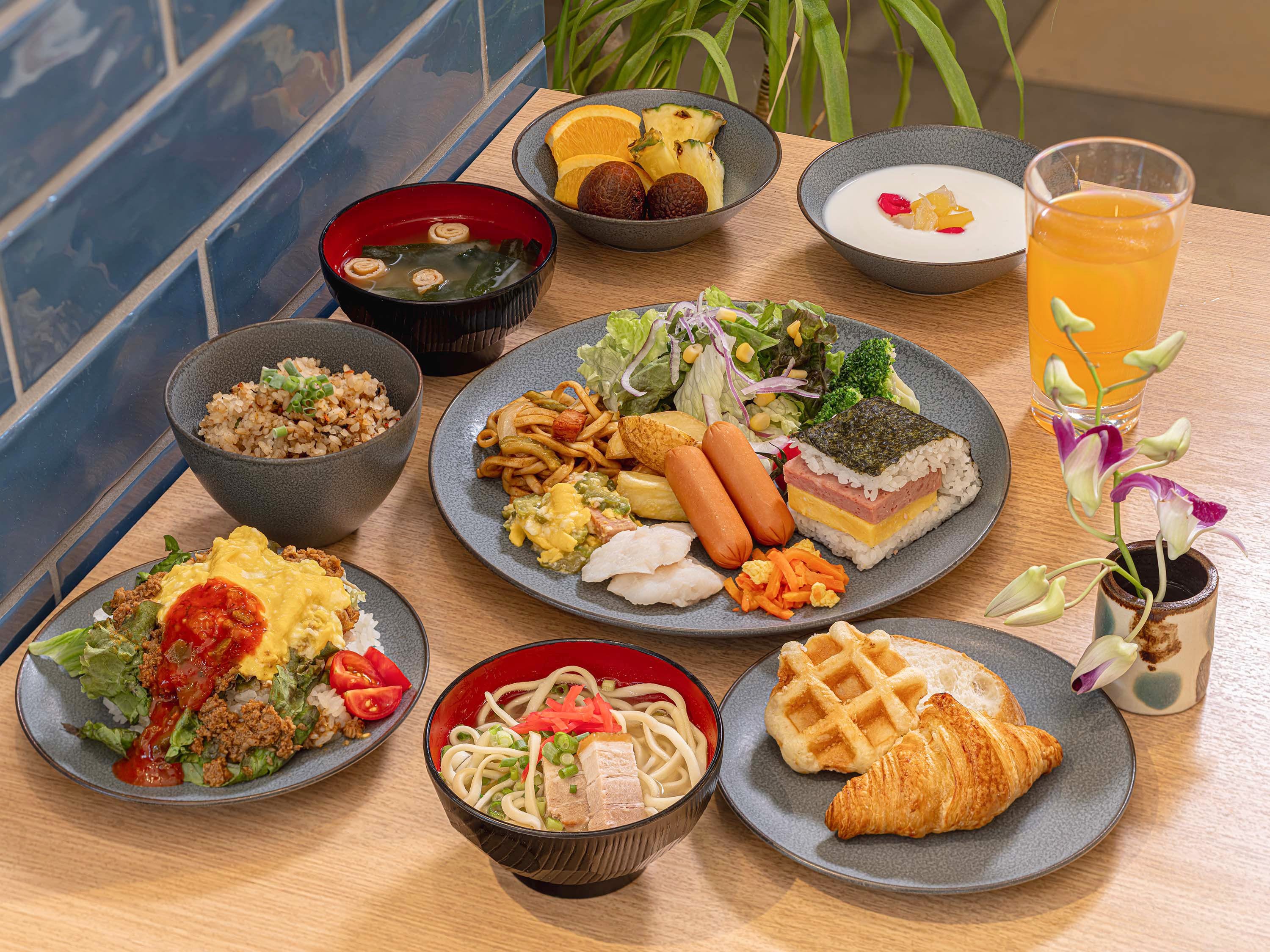 Variedad de platos en una mesa, incluyendo arroz, fideos y un croissant.