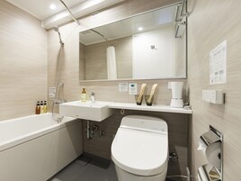 A modern bathroom with a bathtub, sink, toilet, and a large mirror.