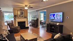 A living room with a fireplace, a television, and a piano. - Beautiful quiet home in cove with dock (Greenwood)