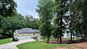 A house with a garage, a driveway, and a lawn. - Beautiful quiet home in cove with dock (Greenwood)