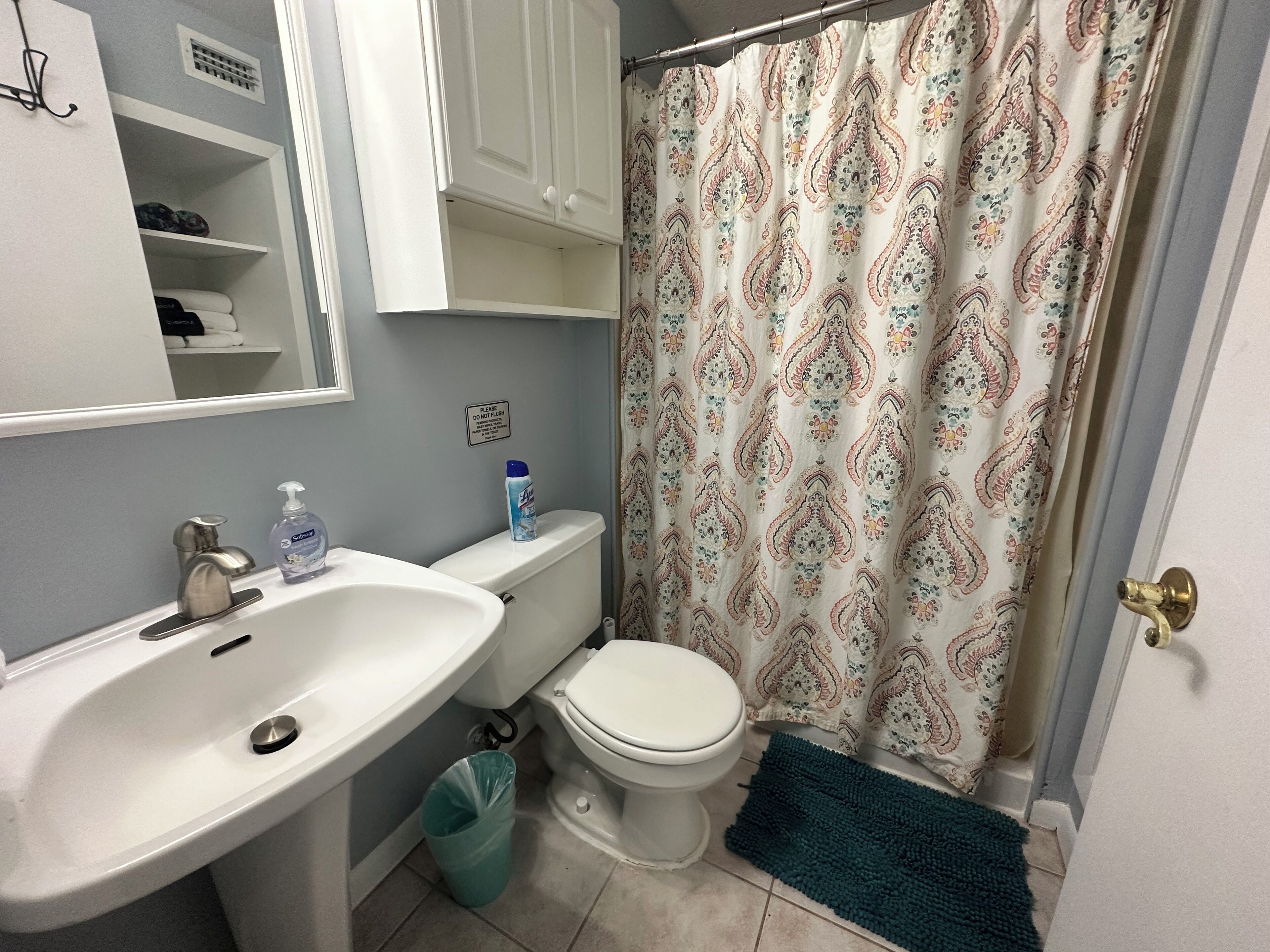 Un baño con lavamanos, inodoro y cortina de ducha blanca.