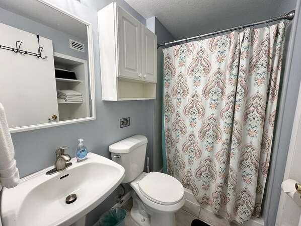 A bathroom with a sink, toilet, and shower curtain. - Unit 3 - Shoreline - Pet-Friendly Crescent Beach Hideaway, Walk to Beach (St. Augustine)