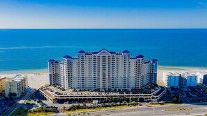 Un hotel de gran altura con varios pisos, una estructura de estacionamiento y vista al mar.