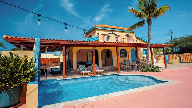 A house with a swimming pool, outdoor seating, and a covered patio area.